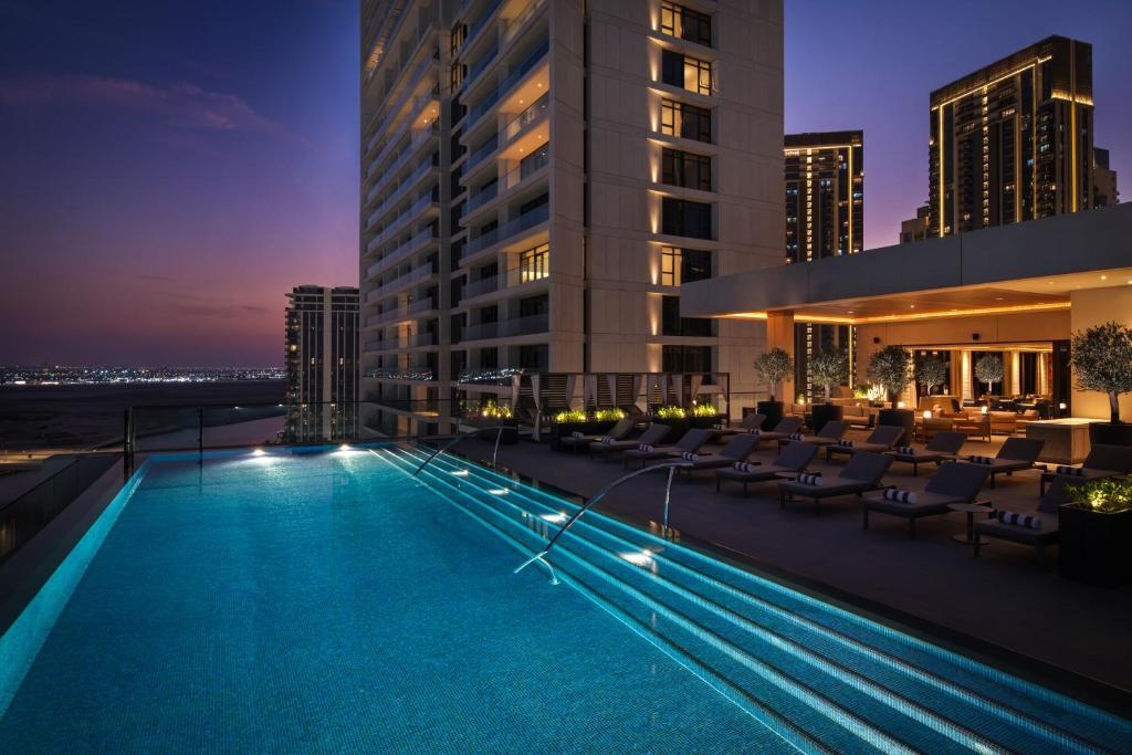 a pool on the rooftop of a building at night at Palace Dubai Creek Harbour in Dubai