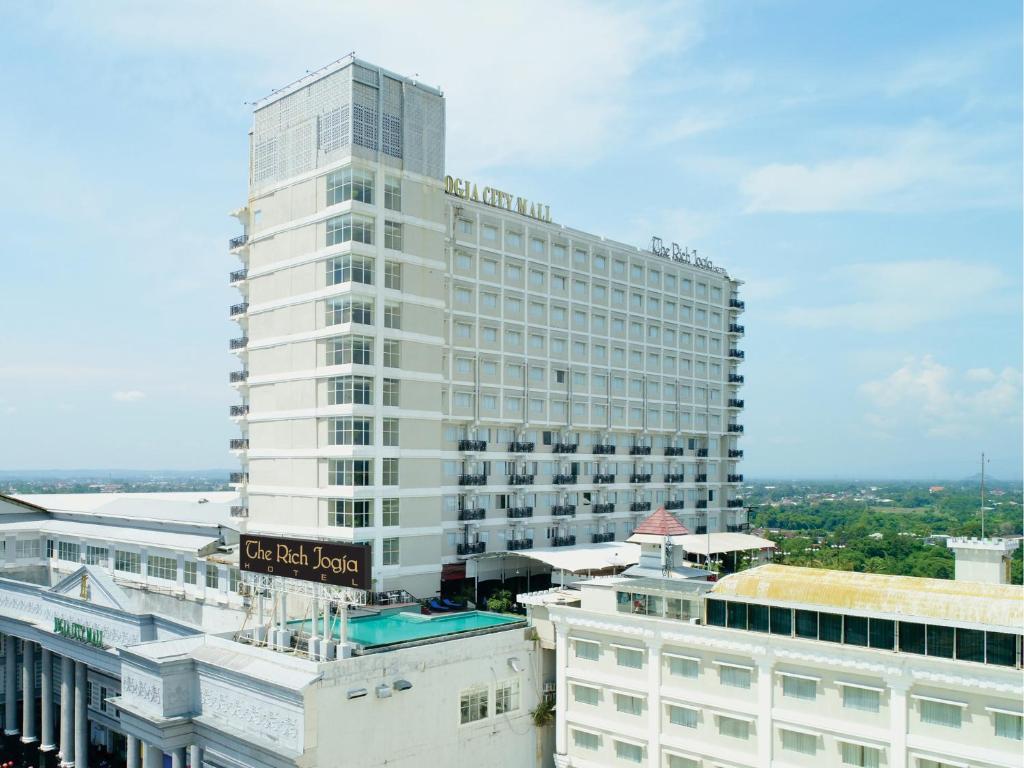 a tall white building with a sign in front of it at The Rich Jogja Hotel in Yogyakarta