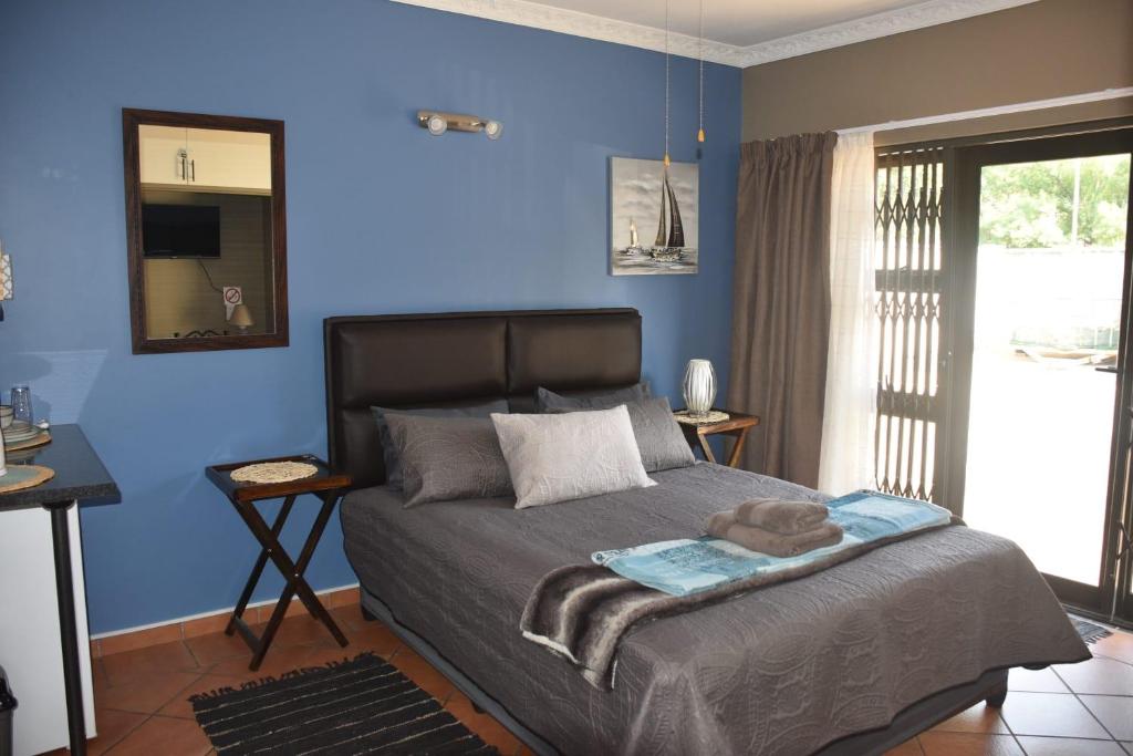 - une chambre avec des murs bleus et un lit avec un miroir dans l'établissement CasaC Guesthouse, à Sasolburg