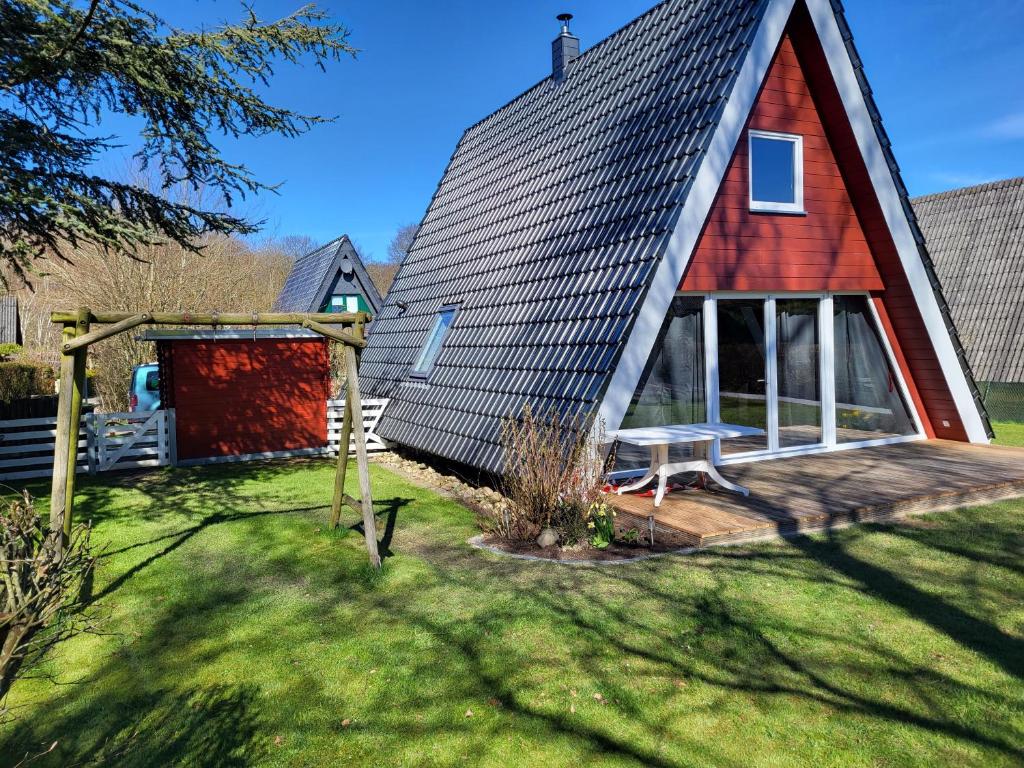 een rood huis met een rood dak en een tuin bij PV Giese Ferienhaus Damp in Damp