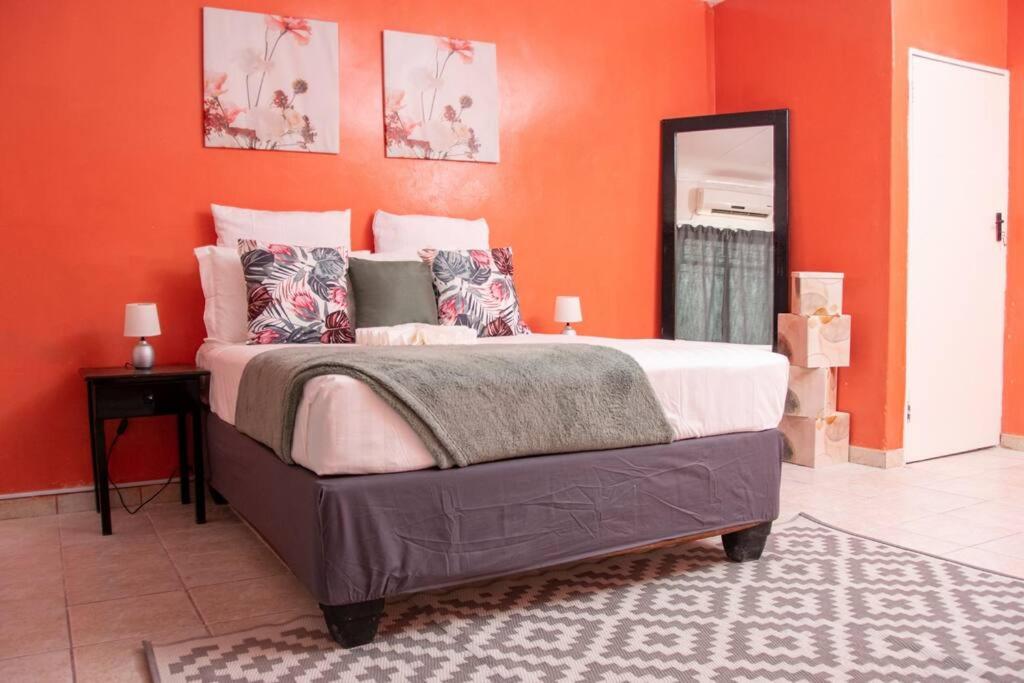 a bedroom with a large bed with an orange wall at Laha Apartment 3 in Maun