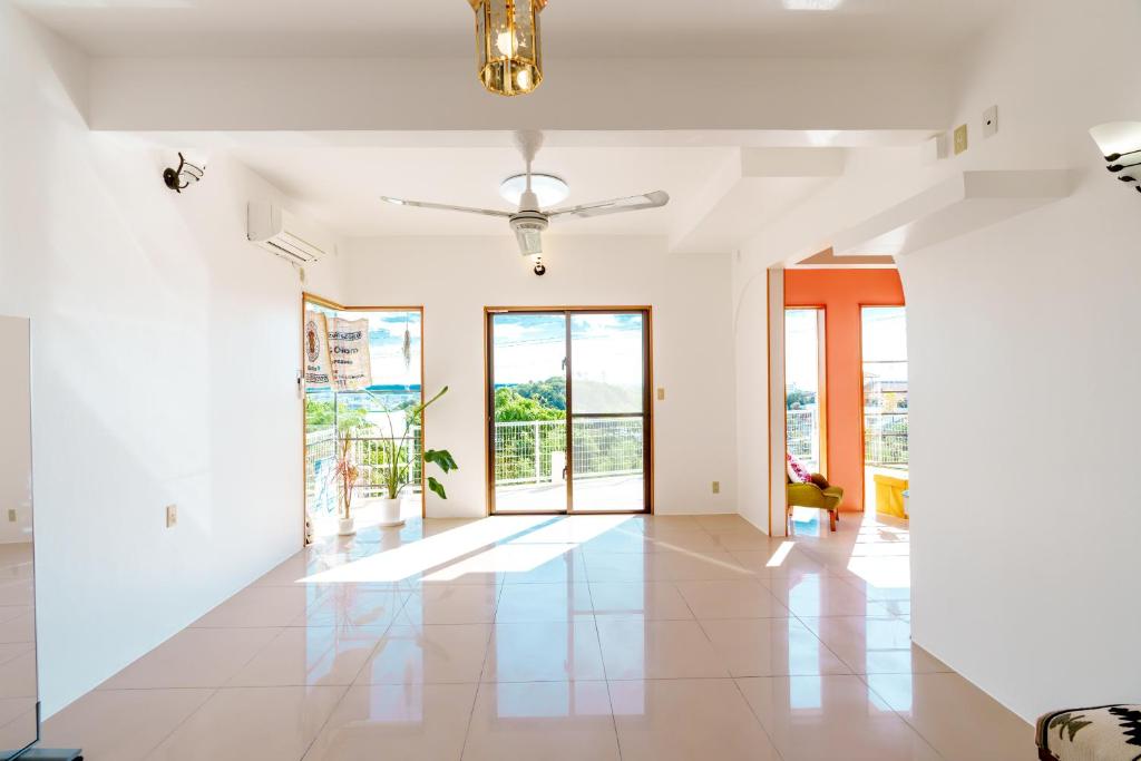 a living room with white walls and a ceiling fan at Tropical Soul Okinawa in Teruya