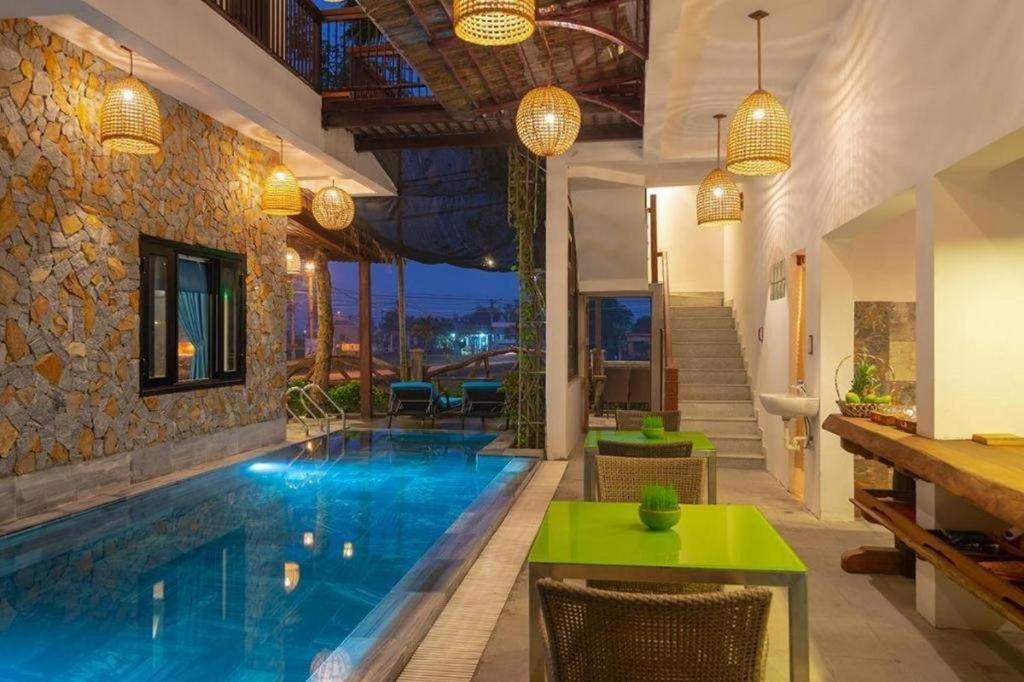 einen Pool in einer Villa mit grünen Tischen und Stühlen in der Unterkunft Gita Boutique Villa in Hoi An