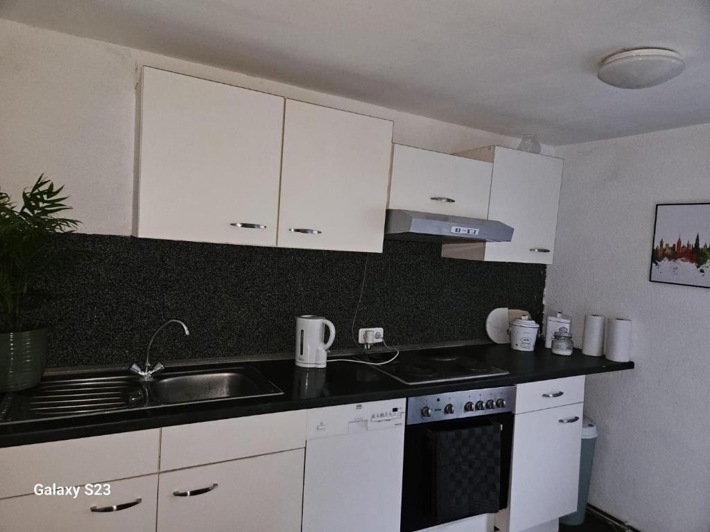 a kitchen with white cabinets and a sink and a stove at Home Sweet Klein ilsede in Ilsede