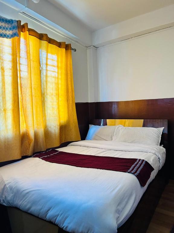 a bedroom with a large bed with yellow curtains at Hotel Sumeru in Kathmandu