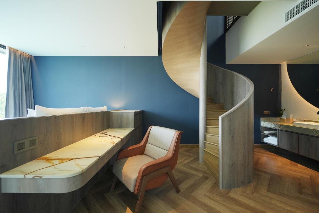 A built-in desk and armchair beside a curved staircase in a split-level suite.