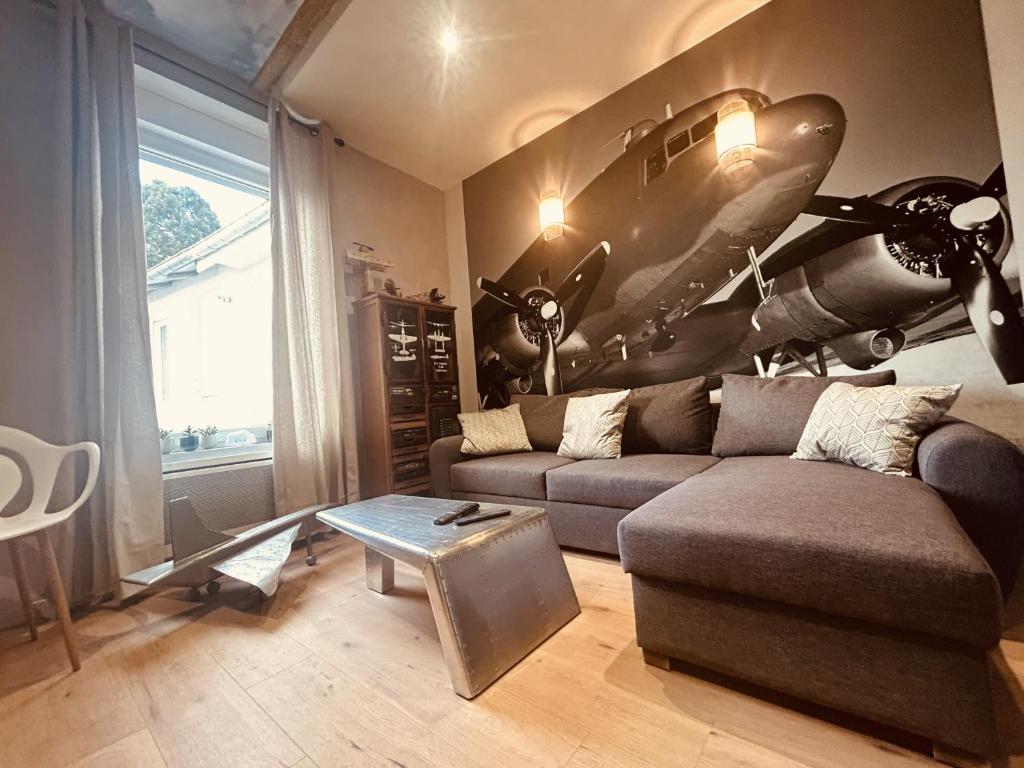 ein Wohnzimmer mit einem Sofa und einem Flugzeug an der Wand in der Unterkunft LA MARIEFACTURE - Comme à la Tour de Contrôle in Boulay - Moselle
