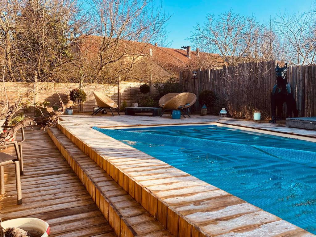a swimming pool with a wooden deck next to at LA MARIEFACTURE - Comm chez Mémé in Laning