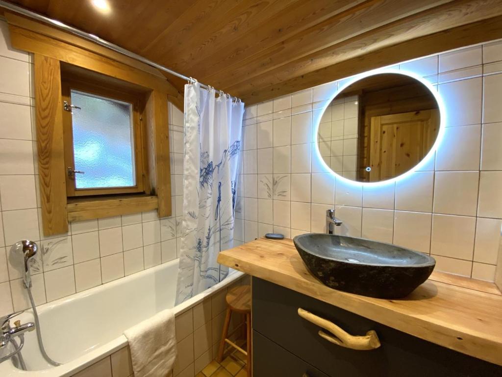 a bathroom with a sink and a mirror and a tub at LE GRAND CERF Chalet en rondins avec SPA Jacuzzi in La Bresse