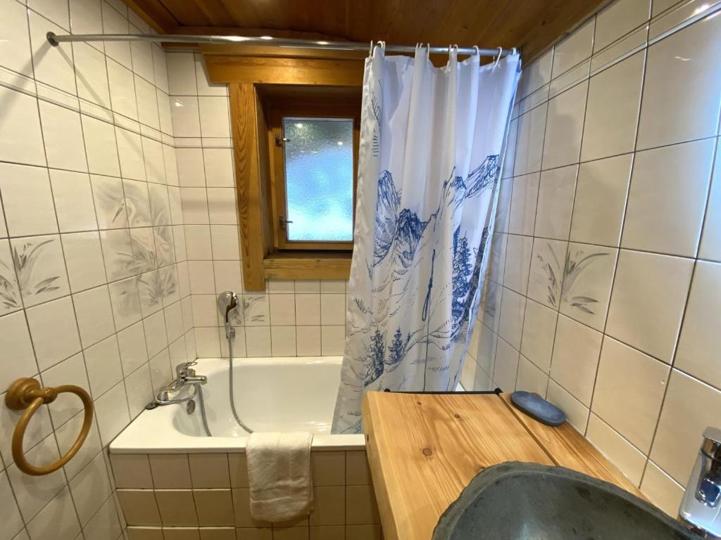 a bathroom with a tub and a shower curtain at LE GRAND CERF Chalet en rondins avec SPA Jacuzzi in La Bresse
