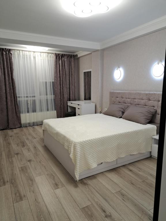 een slaapkamer met een wit bed en een houten vloer bij DECEBAL in Chişinău