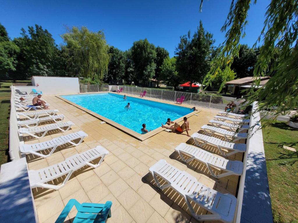 a large pool with lounge chairs and people in it at Camping les Peupliers in Vendays-Montalivet
