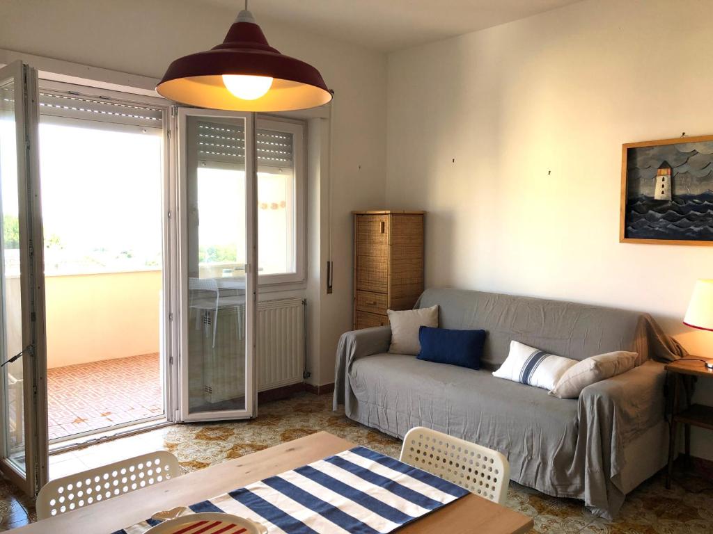 een woonkamer met een bank en een glazen schuifdeur bij Be Your Home - Casa Raffaello in Santa Marinella