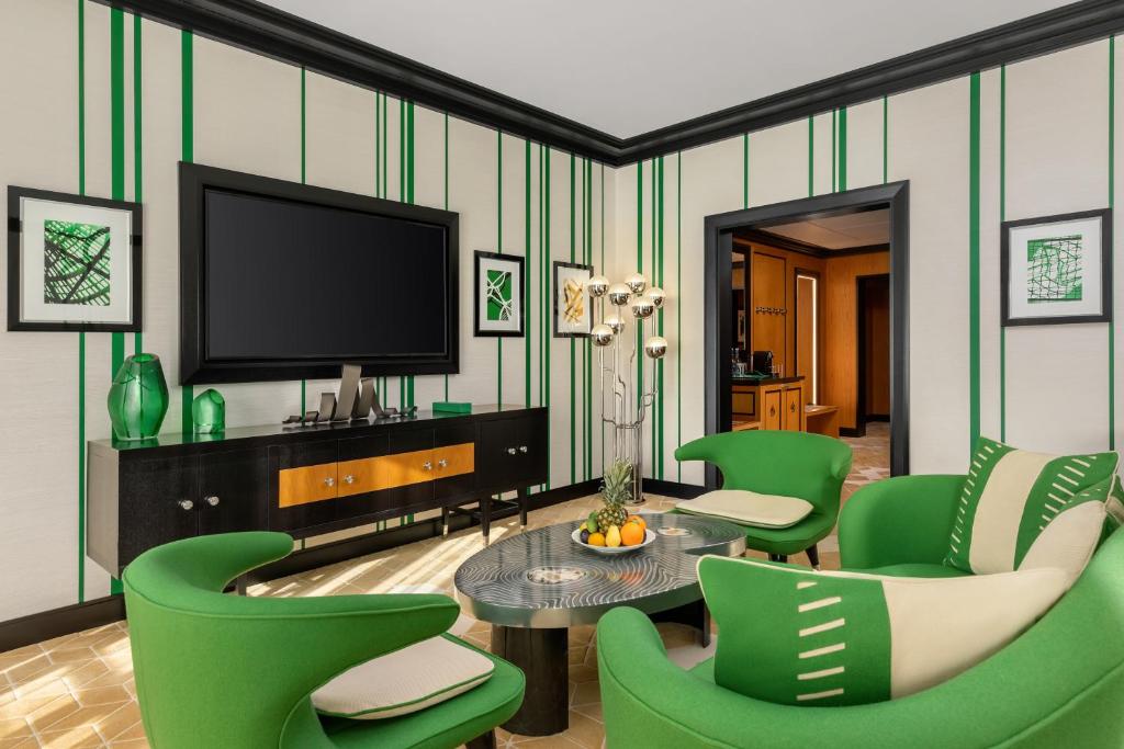 a living room with green chairs and a television at Dinamo Hotel Baku in Baku