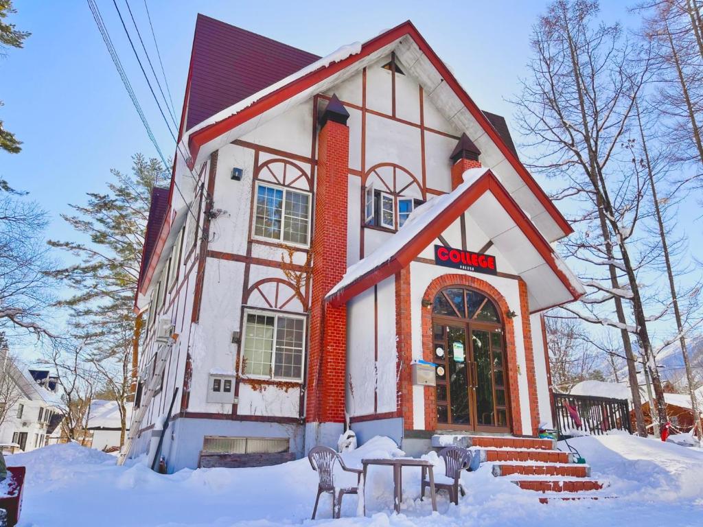 a building with snow in front of it at ペンションcollege白馬 in Hakuba