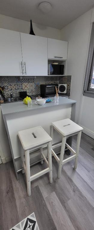 a kitchen with a counter and two stools in it at LOGEMENT CLICHY in Clichy
