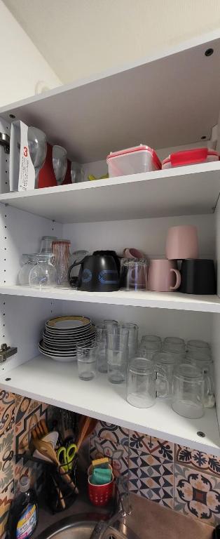 a refrigerator shelf filled with dishes and other items at LOGEMENT CLICHY in Clichy