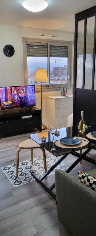 a living room with a couch and tables and a tv at LOGEMENT CLICHY in Clichy