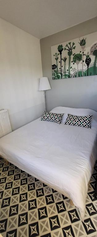 a bedroom with a large white bed with a lamp at LOGEMENT CLICHY in Clichy