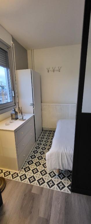 a bedroom with a refrigerator and a tiled floor at LOGEMENT CLICHY in Clichy