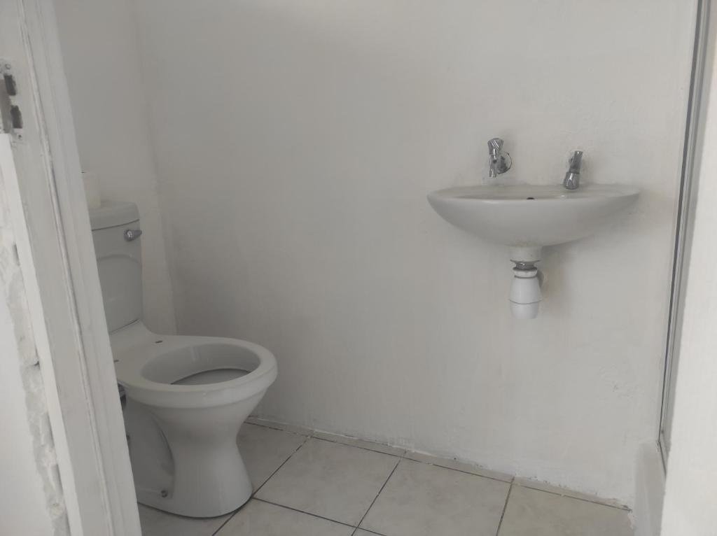 a white bathroom with a toilet and a sink at Tumelos place in Bloemfontein