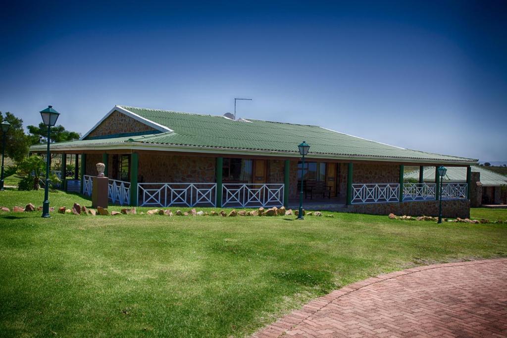 a house with a green roof and a grass yard at Mentors Country Estate in Jeffreys Bay