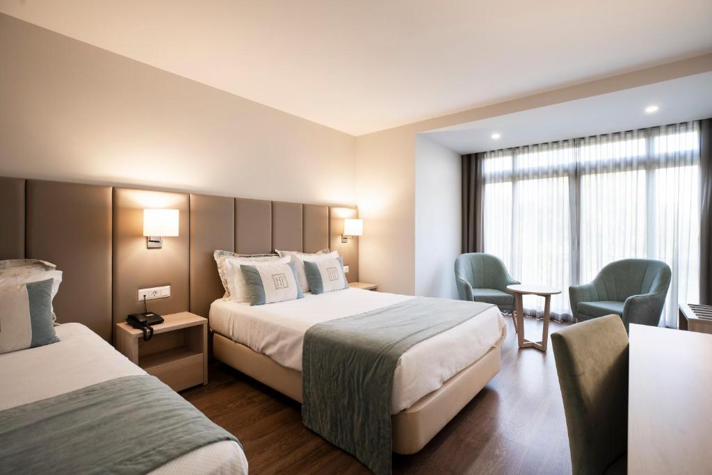 a hotel room with two beds and two chairs at Hotel Fatima in Fátima