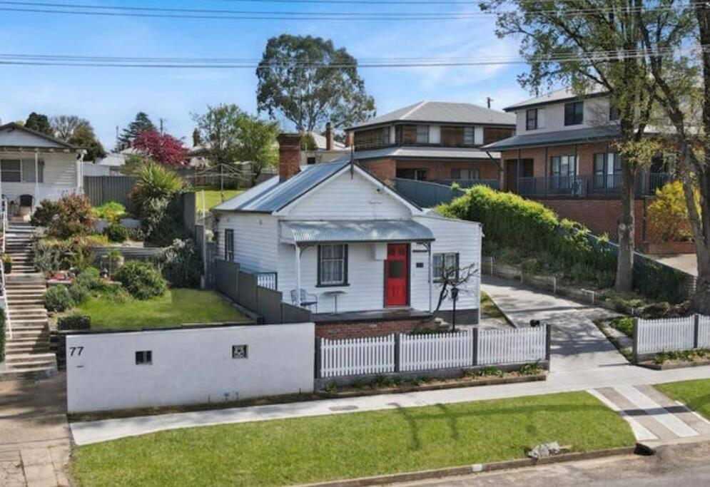 a white house with a red door in a yard at Antique Retreat in Bathurst