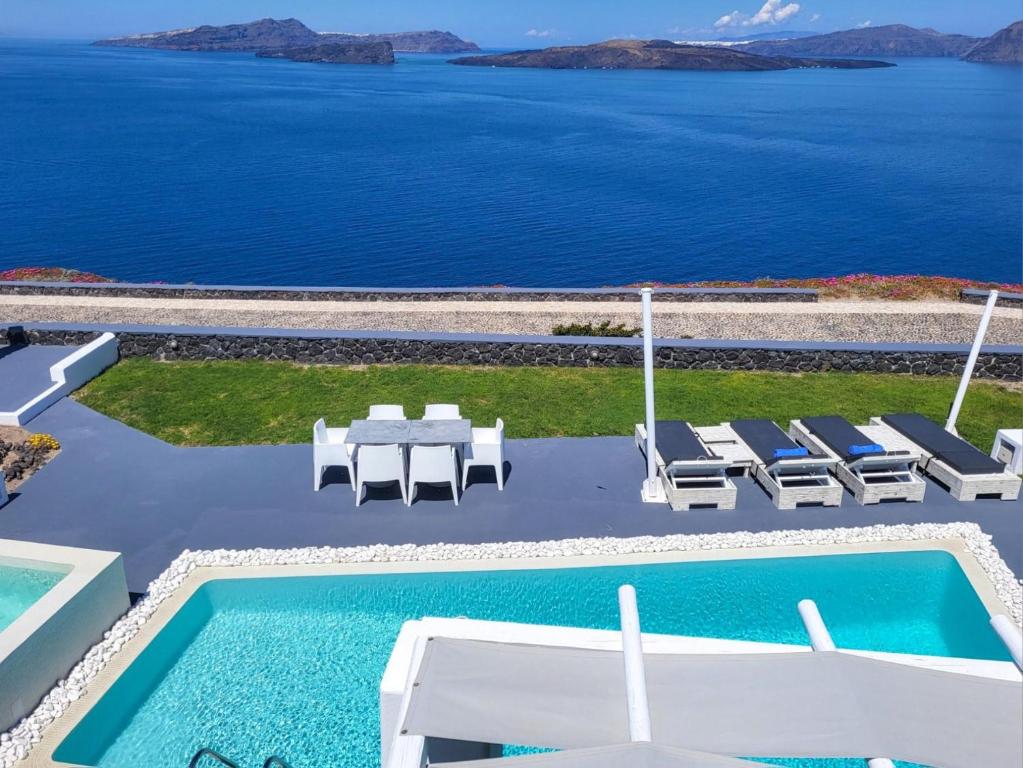 een zwembad met stoelen en een tafel en de oceaan bij Santorini Princess Presidential Suites in Akrotiri