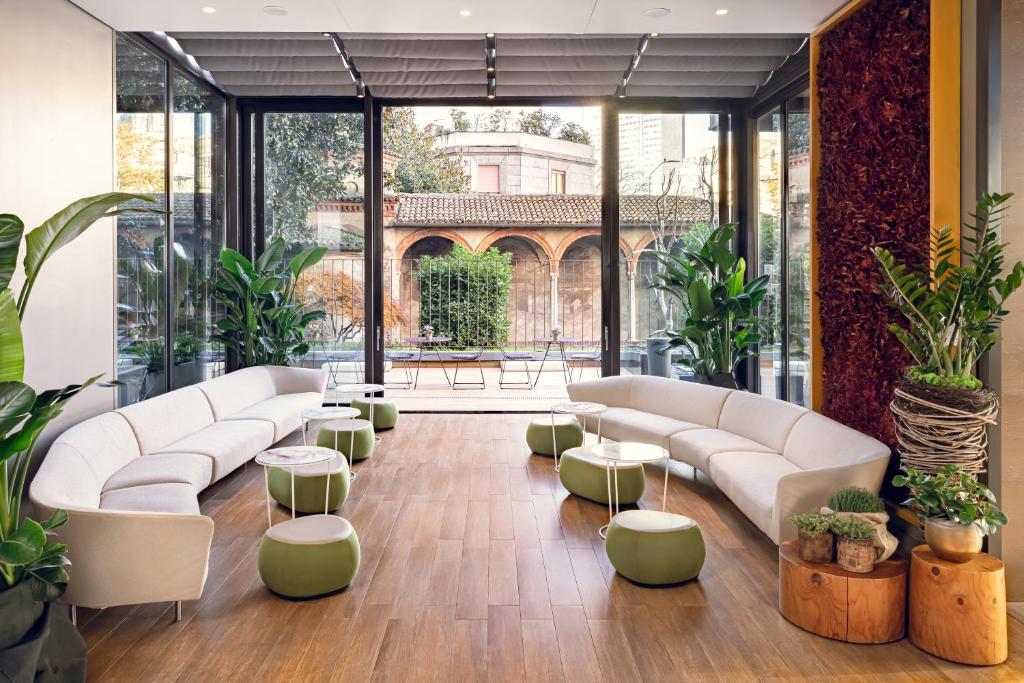 una hall con divani e tavoli bianchi e piante di Starhotels Echo a Milano