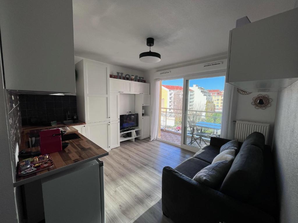 a living room with a couch and a kitchen at Studio terrasse et parking privé in Nice