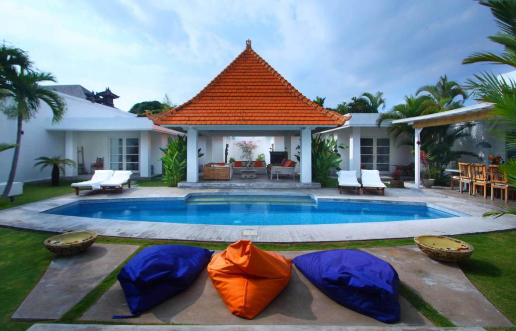 a house with a swimming pool with umbrellas around it at Villa Mutiara Putih by Optimum Bali Villas in Seminyak