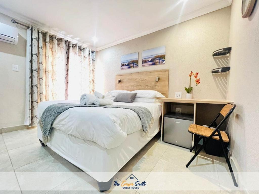 een witte slaapkamer met een groot bed en een bureau bij The Curve Suite Guest House 
