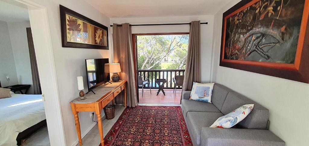 a bedroom with a bed and a couch and a desk at Laguna Beach K60 - Greenways Golf Estate on Sea in Cape Town