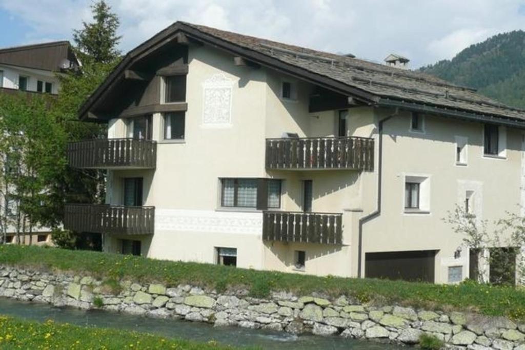 a white building with balconies on the side of a river at Chesa Margretta, Studio im 1 Obergeschoss in Sils Maria