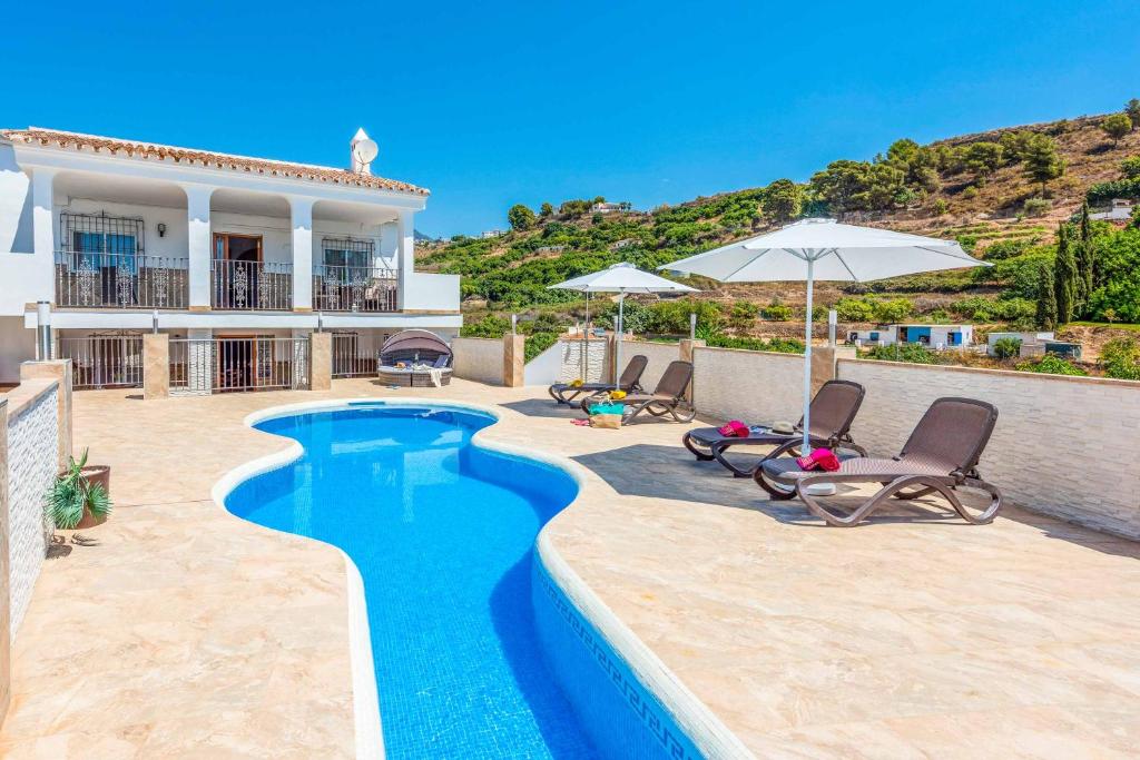 une villa avec une piscine dotée de chaises et de parasols dans l'établissement Villa Dos Hermanas, à Frigiliana