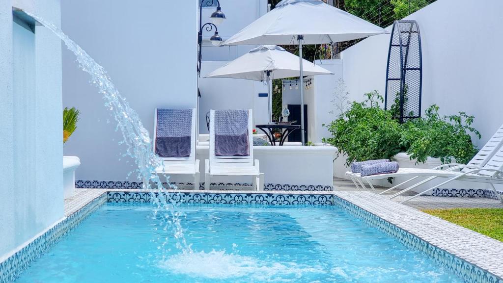 einen Pool mit einem Brunnen in einem Garten mit Stühlen und einem Sonnenschirm in der Unterkunft Batavia Boutique Hotel in Stellenbosch