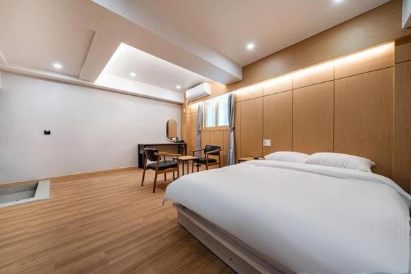 Un dormitorio con una gran cama blanca y una mesa en Lime Hotel, en Busan