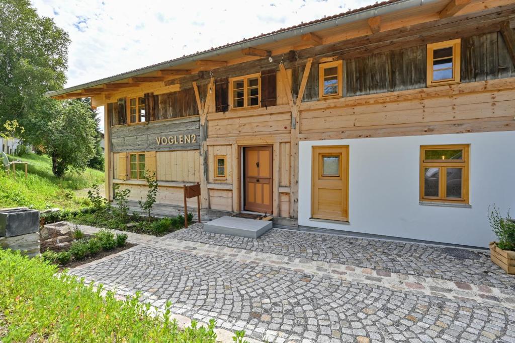 ein Holzhaus mit einer steinernen Einfahrt davor in der Unterkunft Voglen 2 in Nesselwang