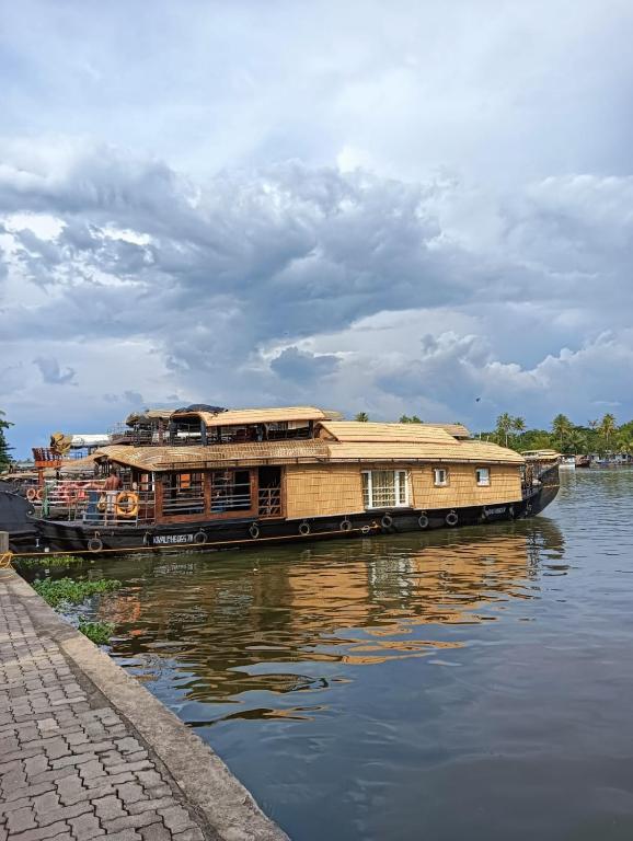 a house boat parked on the water next to a sidewalk at Lakenest overnight in Alleppey