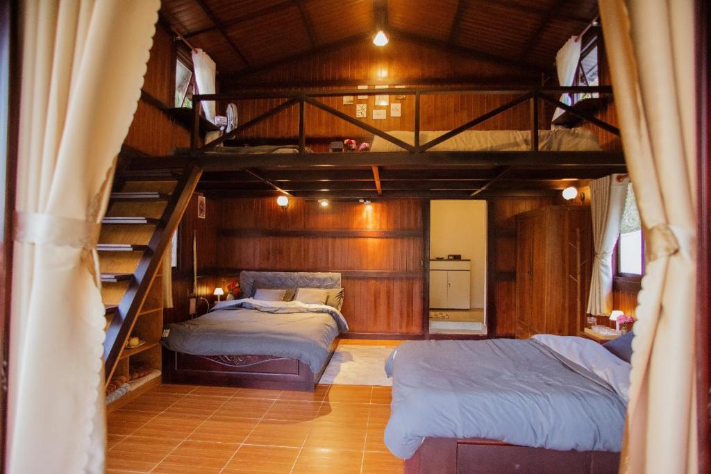2 bedden in een kamer met een stapelbed bij Một căn nhà gỗ ấm áp in Xuan An