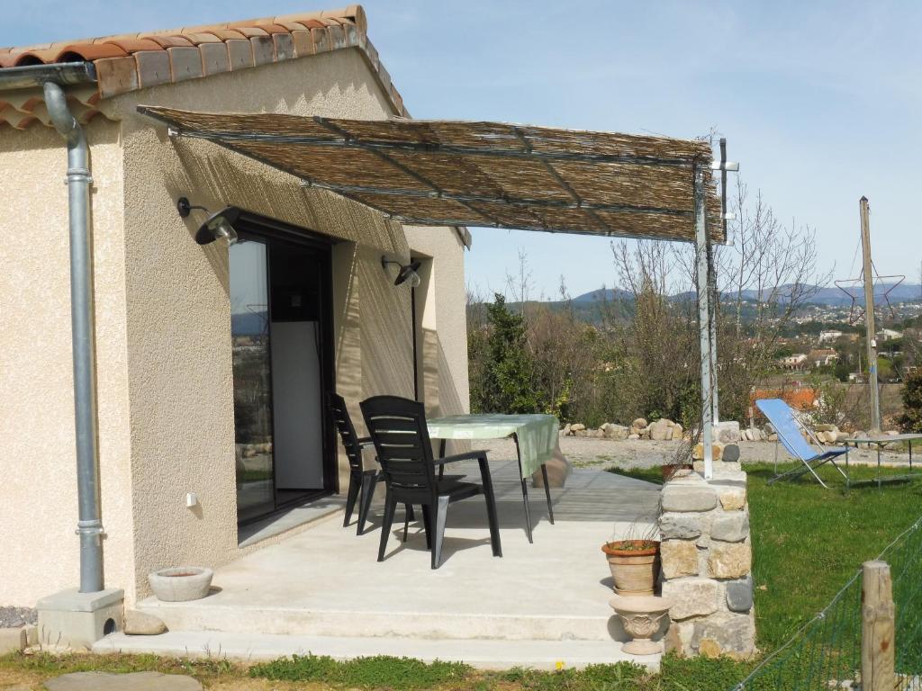 a patio with a table and chairs under a roof at Gîte Amour D&#39;ardèche in Saint-Sernin