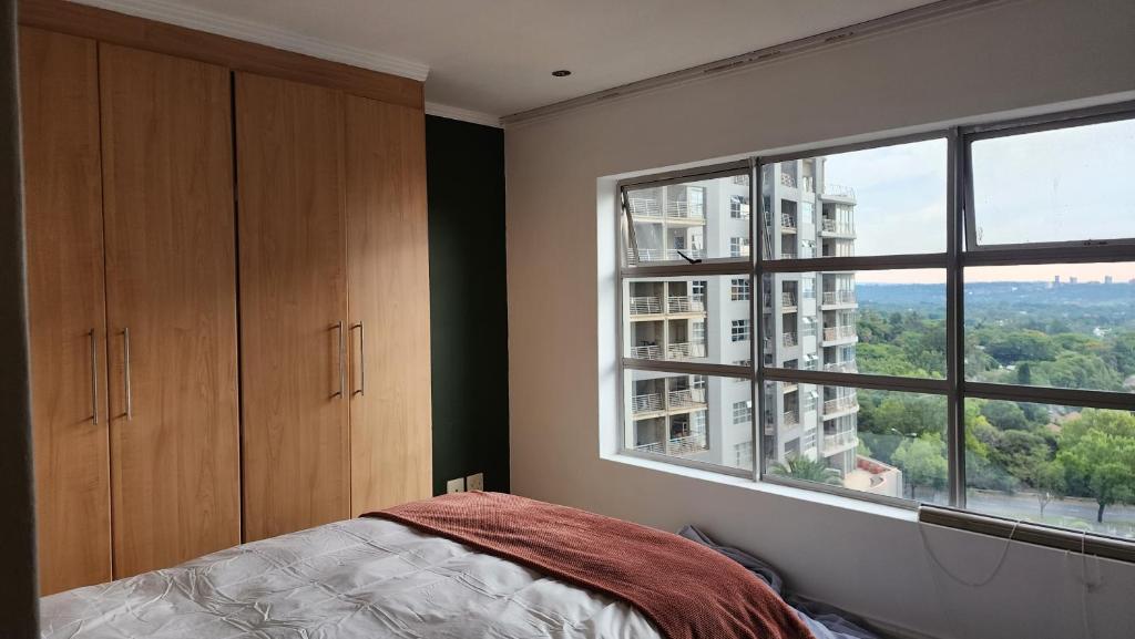 a bedroom with a bed and a large window at Sandhurst Towers in Johannesburg