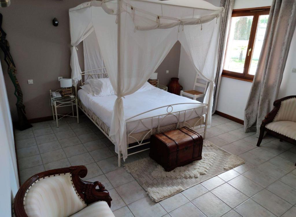 a bedroom with a canopy bed and a chair at Logis Hôtel & Spa Le Saint Antoine in Lamarche-sur-Saône