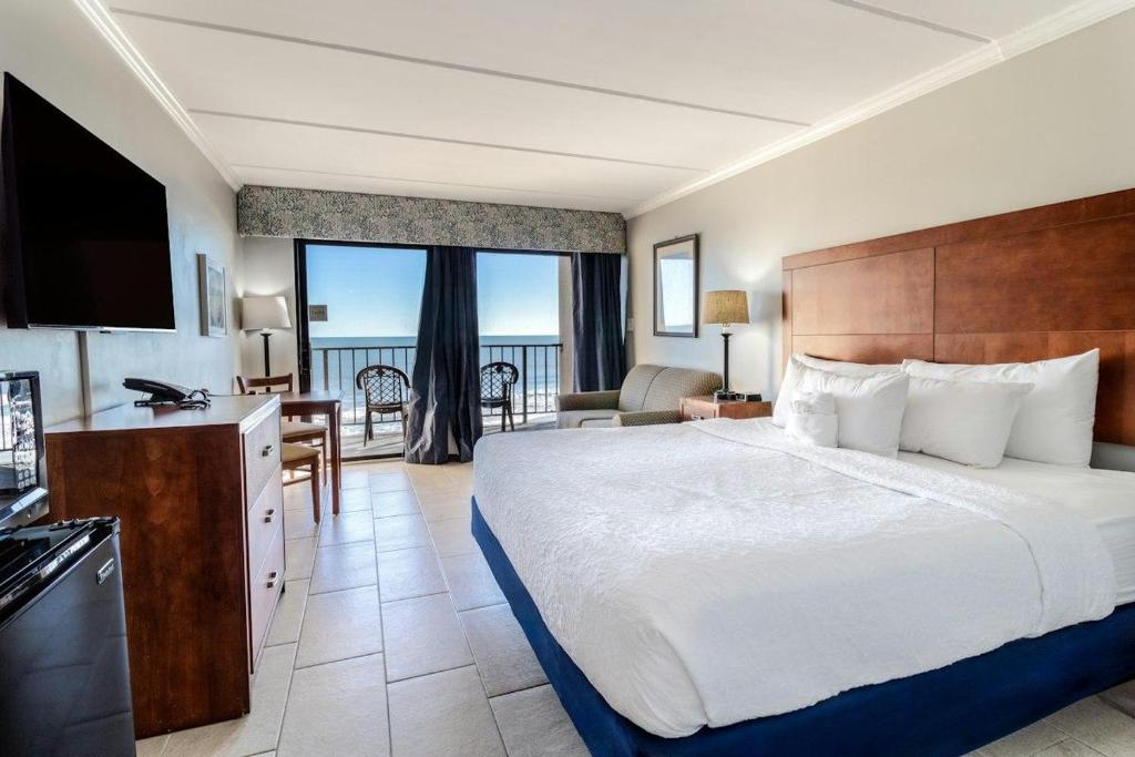 Una habitación de hotel con una cama grande y un balcón. en Attractive Oceanfront King Room 5th Flr, en Pawleys Island
