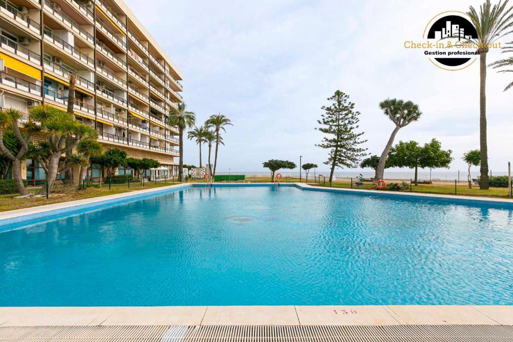 a large blue swimming pool next to a building at Apartamento Castillo Santa Clara 1º Linea El Trasval in Torremolinos