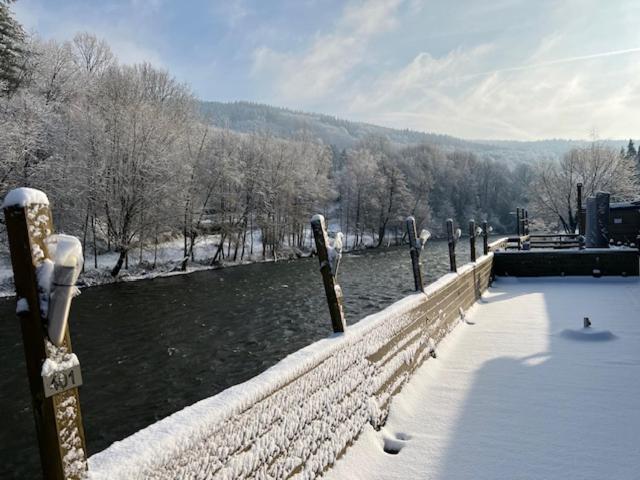 a fence with snow on it next to a river at Hotel Val De La Cascade in Stavelot