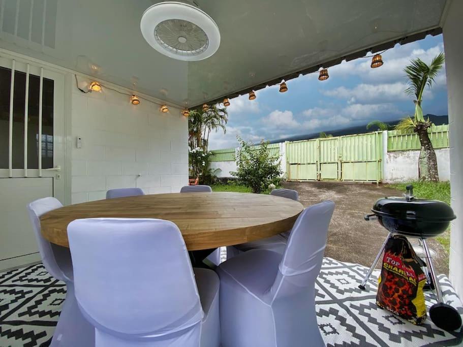 d'une terrasse avec une table en bois et des chaises blanches. dans l'établissement La Tit'Kaz Bégonia (Vue montagne), à Saint-Philippe