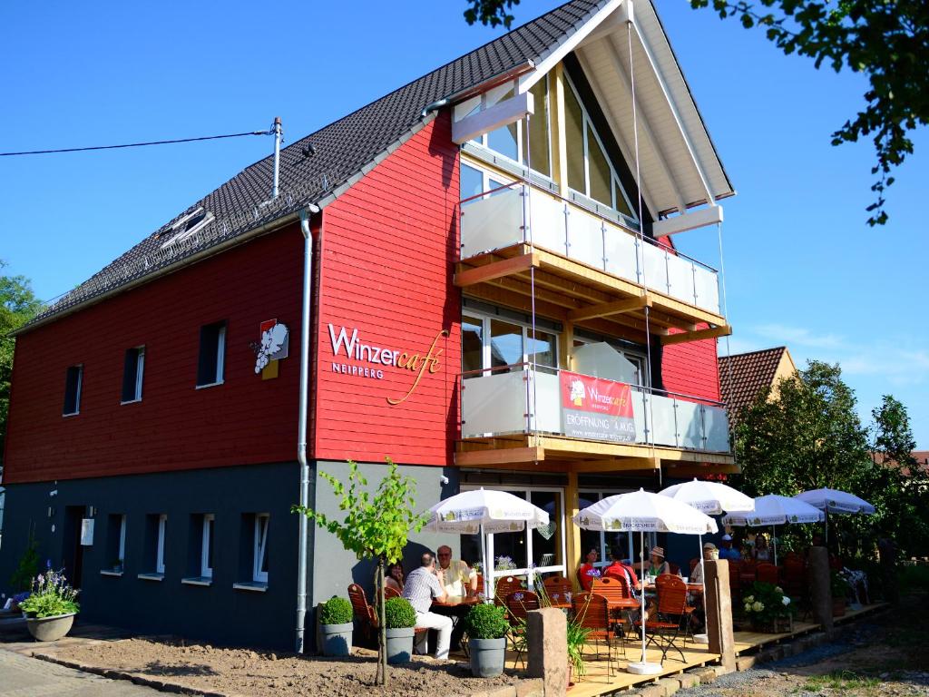 um edifício vermelho com pessoas sentadas fora dele em Winzercafe Neipperg Ferienwohnungen em Brackenheim