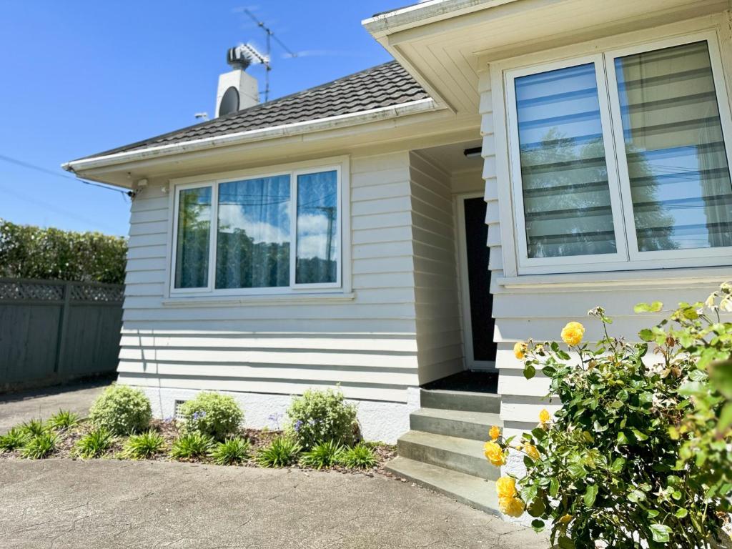 a white house with a window and a driveway at Charming & Modern 4 BR in Lower Hutt